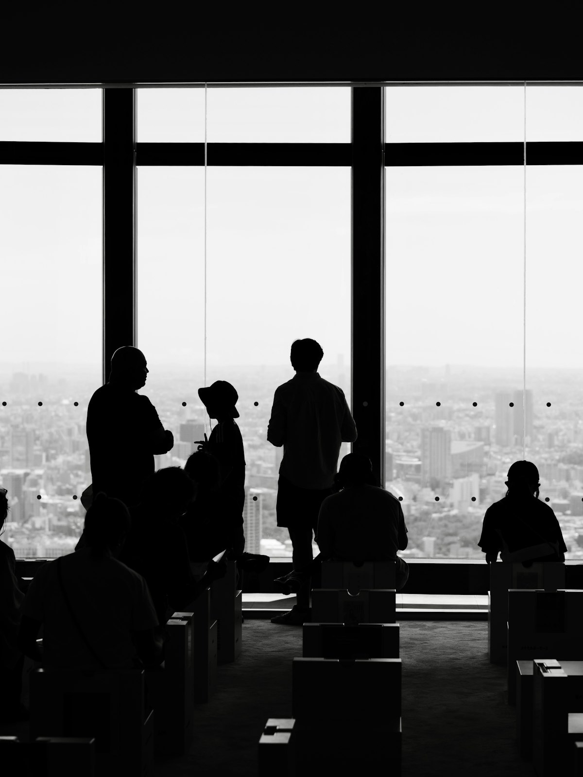 Silhouetted figures surveying the city from a glass tower
